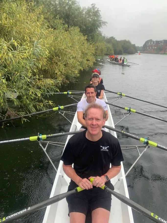 Jon rowing with a crew on the river